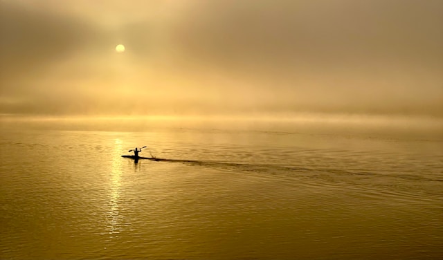 A kayak rowing into the sunrise.
